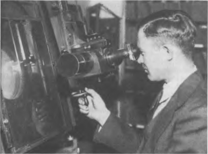 Рис. 8.4. Блинк-компаратор Ловелловской обсерватории производства фирмы «Карл Цейсс» (Германия), за которым Клайд Томбо провел 700 часов в поисках новой планеты. На фото, сделанном около 1950 г., Томбо демонстрирует, как он открывал Плутон в 1930 г