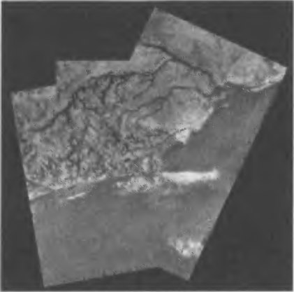 Рис. 8.14. Мозаика из фотографий поверхности Титана, полученных «Гюйгенсом» при спуске на парашюте. Вверху — светлая гористая местность, пронизанная руслом реки с притоками. В нижней части — более темная плоская низменность, куда впадает «река». В момент съемки русло было сухим. Вероятно, в периоды редких, но мощных дождей его заполняют потоки метана